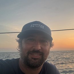 Captain Jason Pisaro at sea at sunset, wearing an American Sailing cap