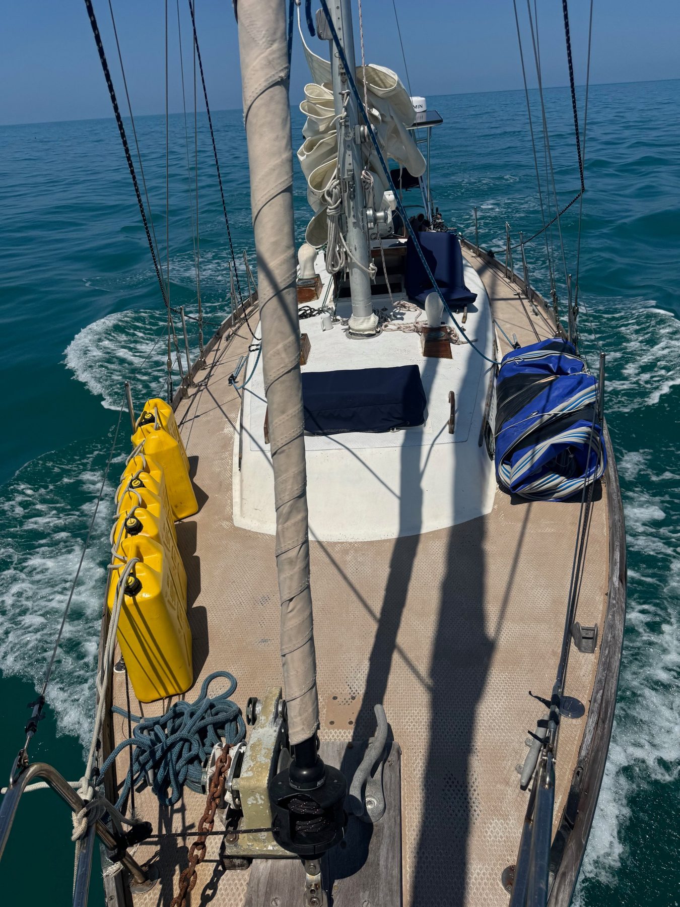 Looking down Yemaya's deck from the mast as she sails through turquoise water