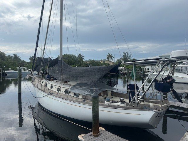 Yemaya at the dock under a cloudy sky, shade cover rigged over the cockpit
