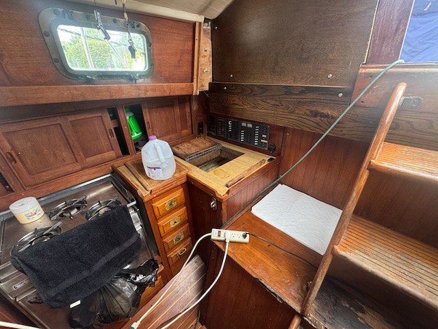 Yemaya's galley with a gas stove, teak cabinets, and the companionway ladder