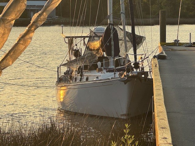 Yemaya's bow lit by golden evening light at a wooden dock