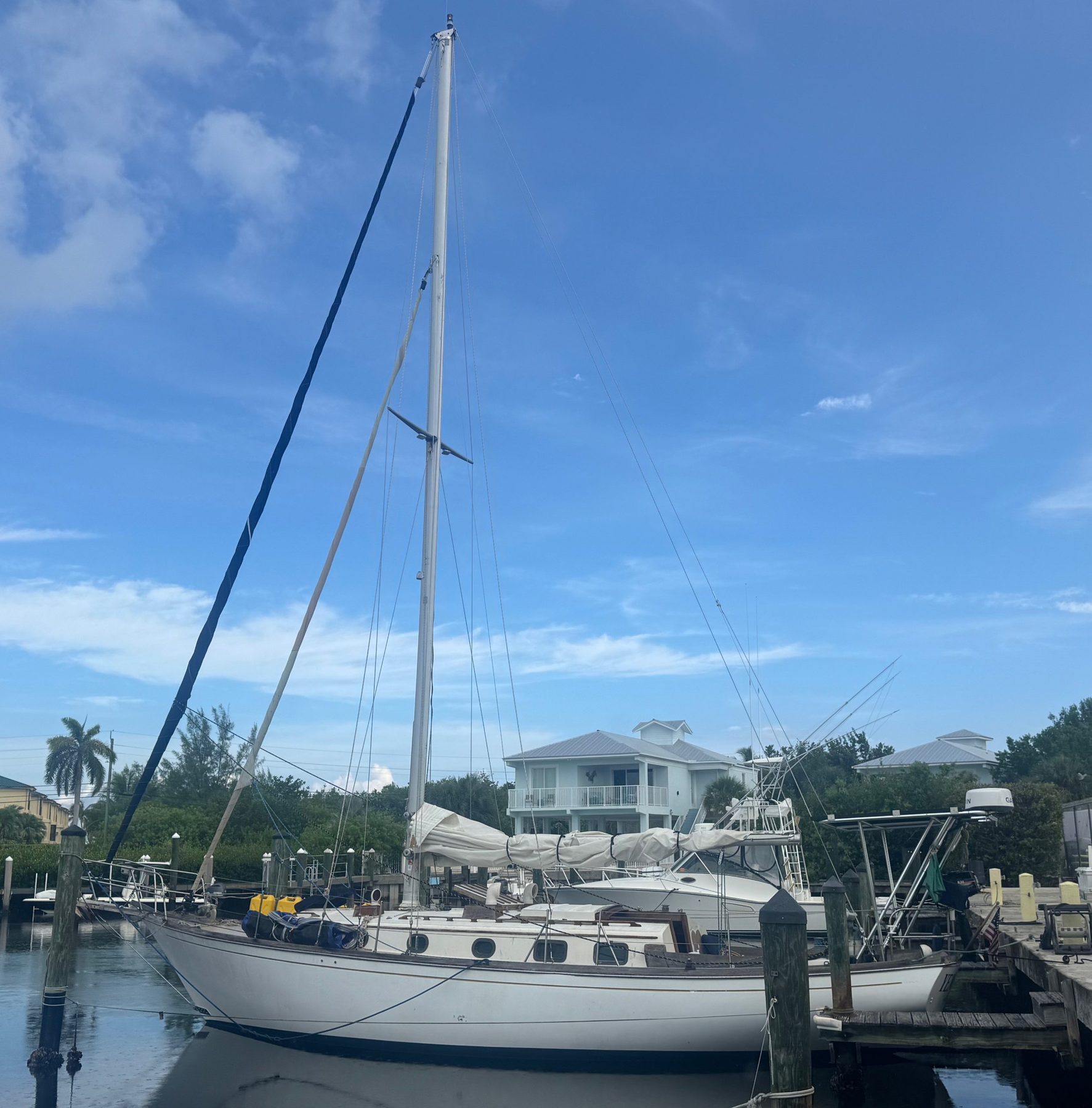 Yemaya tied up at her dock under a bright blue sky, her mast towering over the marina